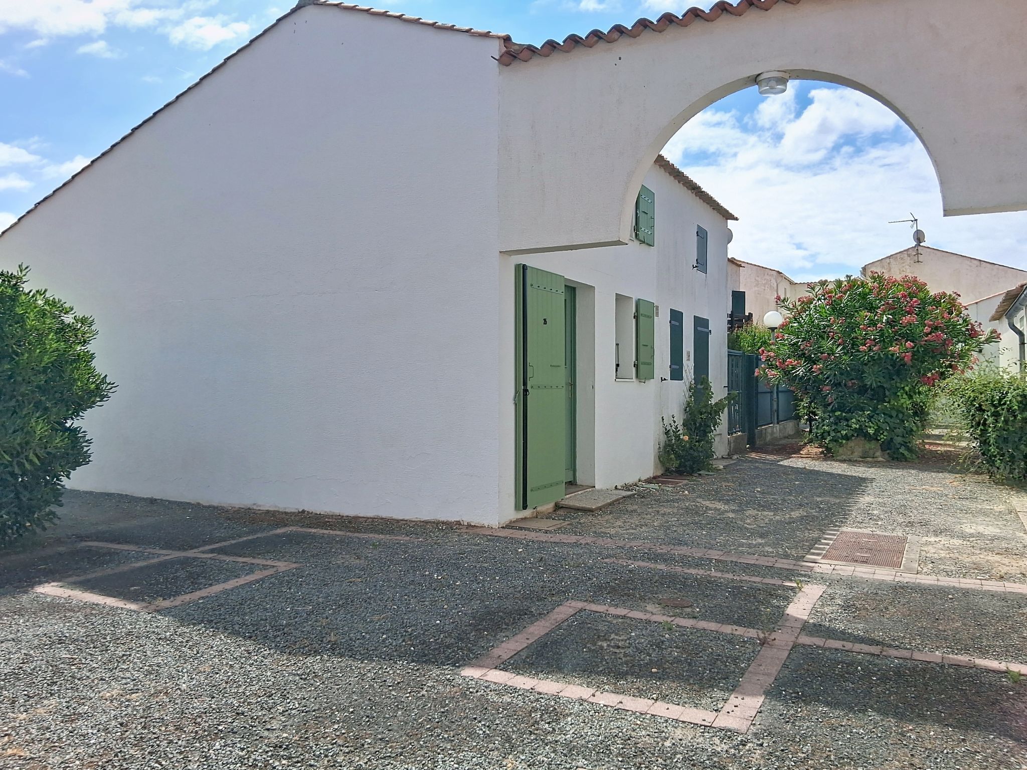 Un edificio bianco con una porta verde, una piccola finestra e un arco.