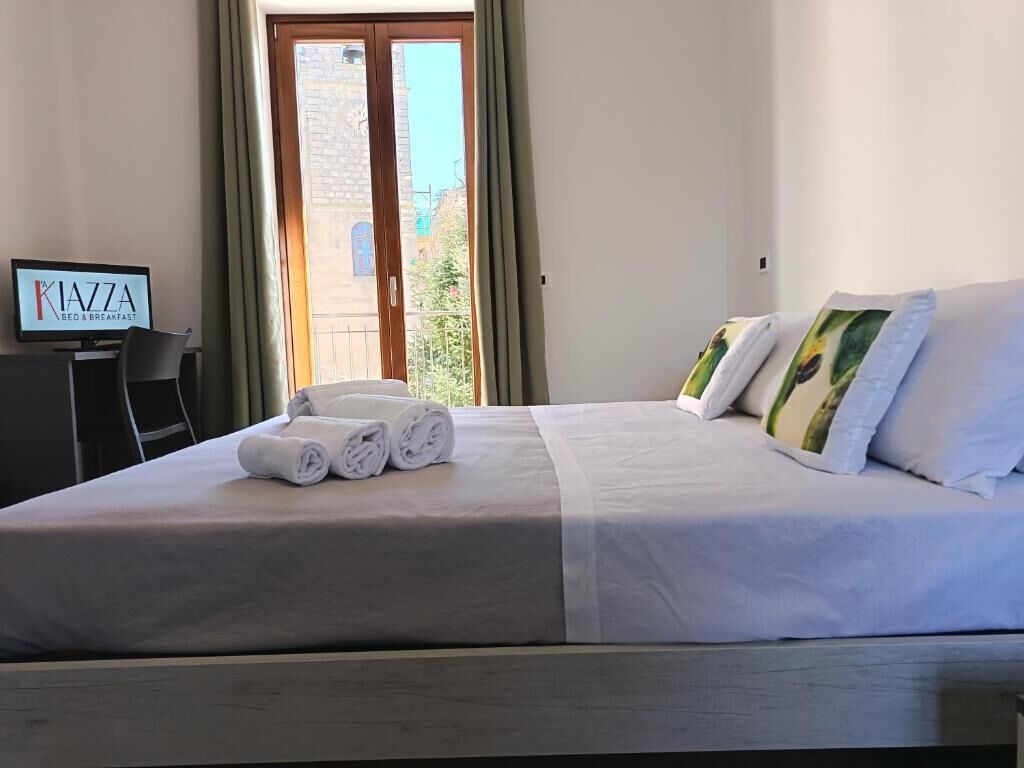 Ein Hotelzimmer mit Bett, Fernseher und Blick ins Freie.