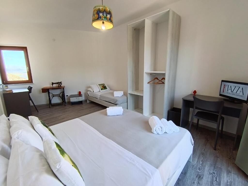 Una habitación de hotel con cama, escritorio, silla, televisor y armario.