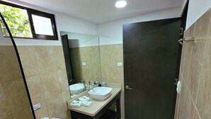 Ein Badezimmer mit Toilette, Bidet und Waschbecken, einer dunklen Tür sowie einer Glasdusche.