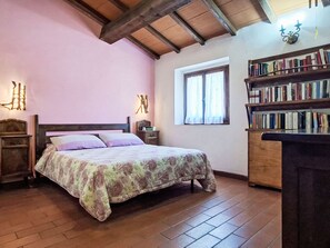 A bedroom with a bed, wooden floor, bookshelves, a window with curtains, and wall-mounted lights. - Vacation home Luce by Interhome (Dicomano)