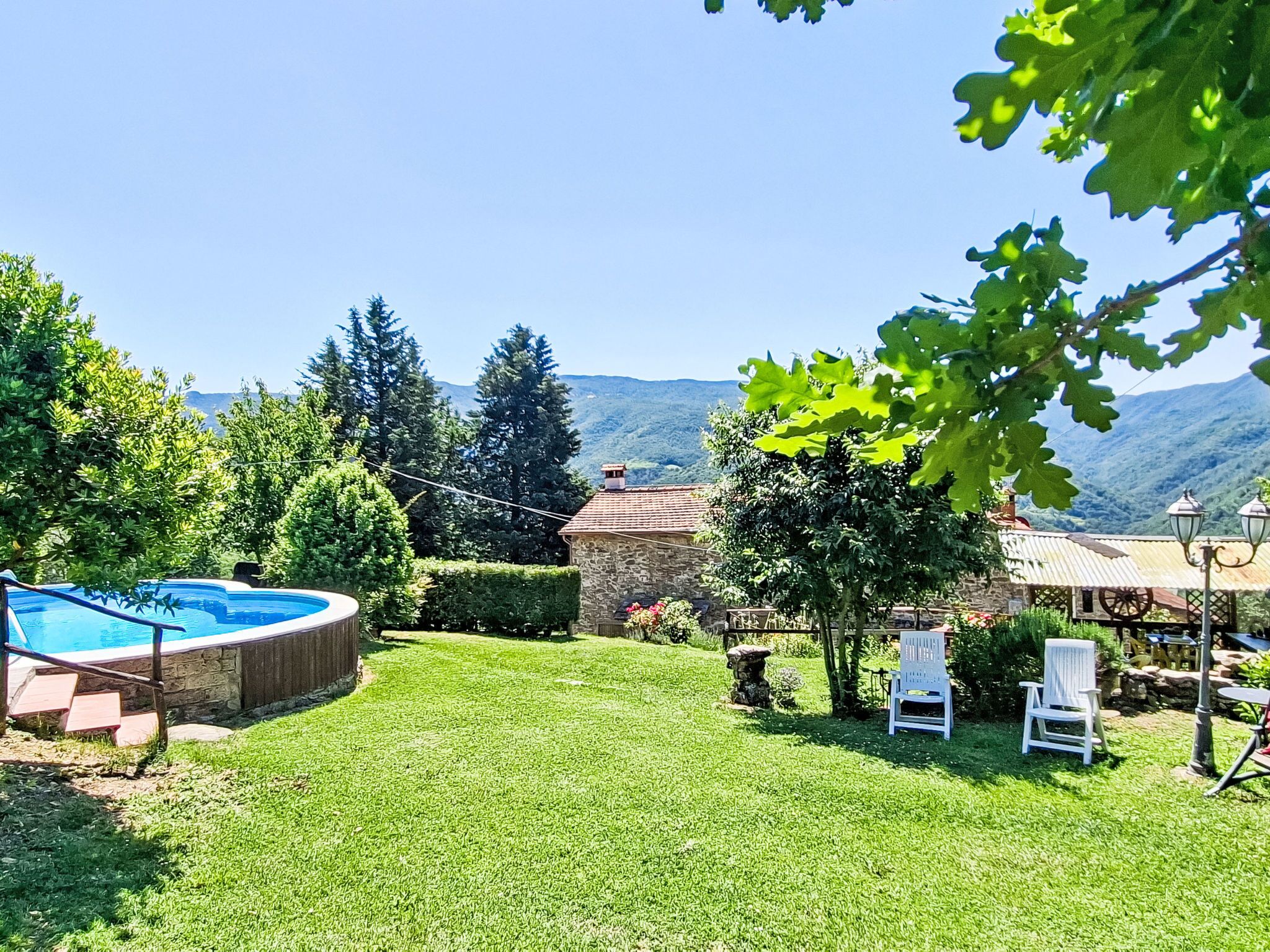 A backyard with a swimming pool, stone house, and chairs.