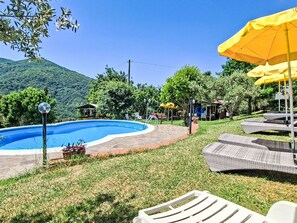 A swimming pool with a surrounding deck, lounge chairs, and umbrellas. - Vacation home Luce by Interhome (Dicomano)