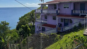 A multi-story building with balconies, a red roof, and a view of the ocean.