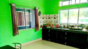 A kitchen with green walls, a dining table, chairs, and a window with curtains. - Tenzin Homestay — Cozy Stay with Free Wi-Fi, Parking & Mountain Views in Dirang (Dirang)