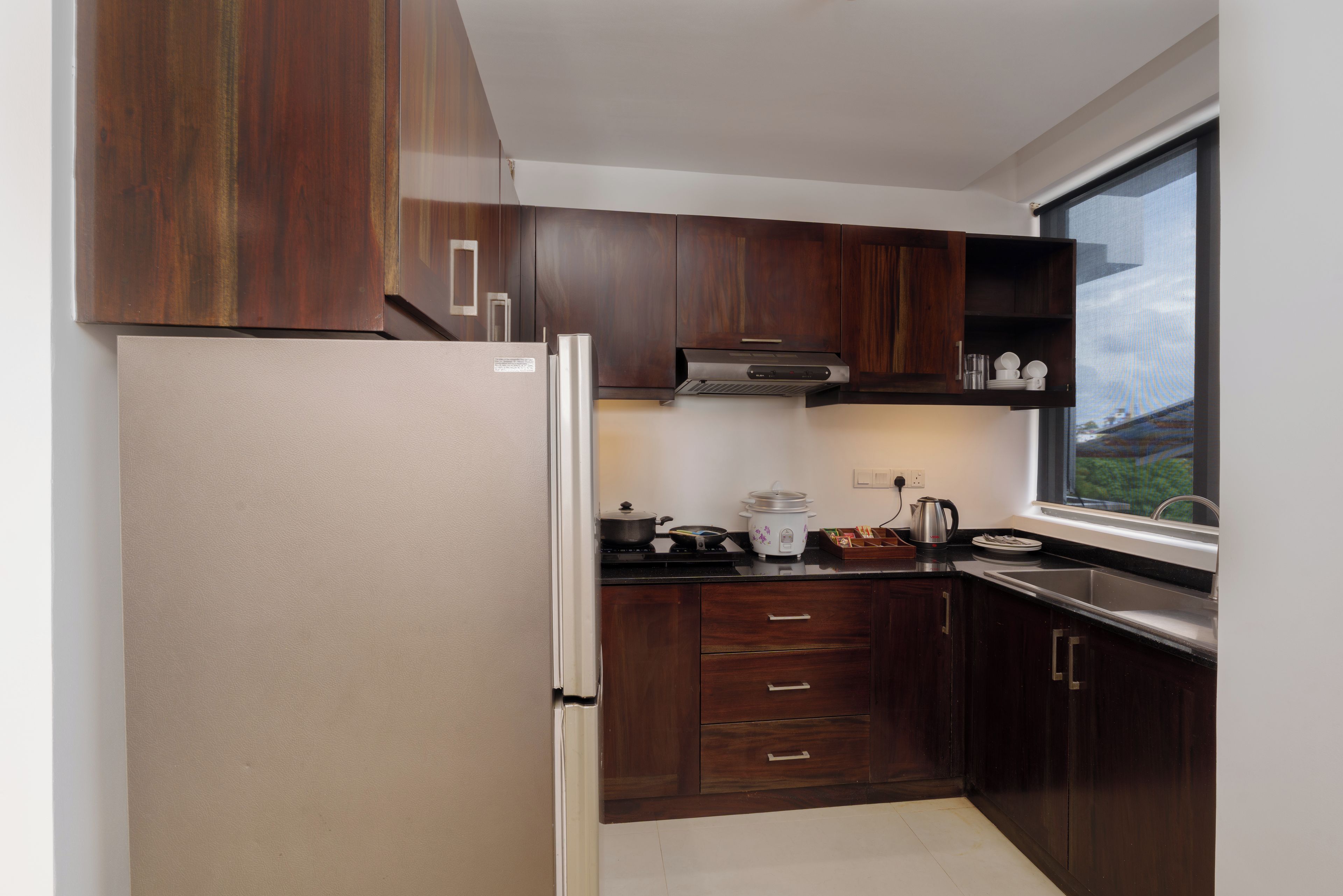 A modern kitchen with wooden cabinets, a stainless steel refrigerator, and a window providing a view of the outdoors.