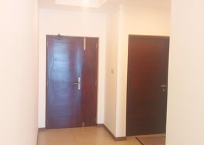 A hallway with two closed doors, one with a visible handle and lock, and the other with a visible latch. The walls are plain and there is a light fixture on the ceiling.