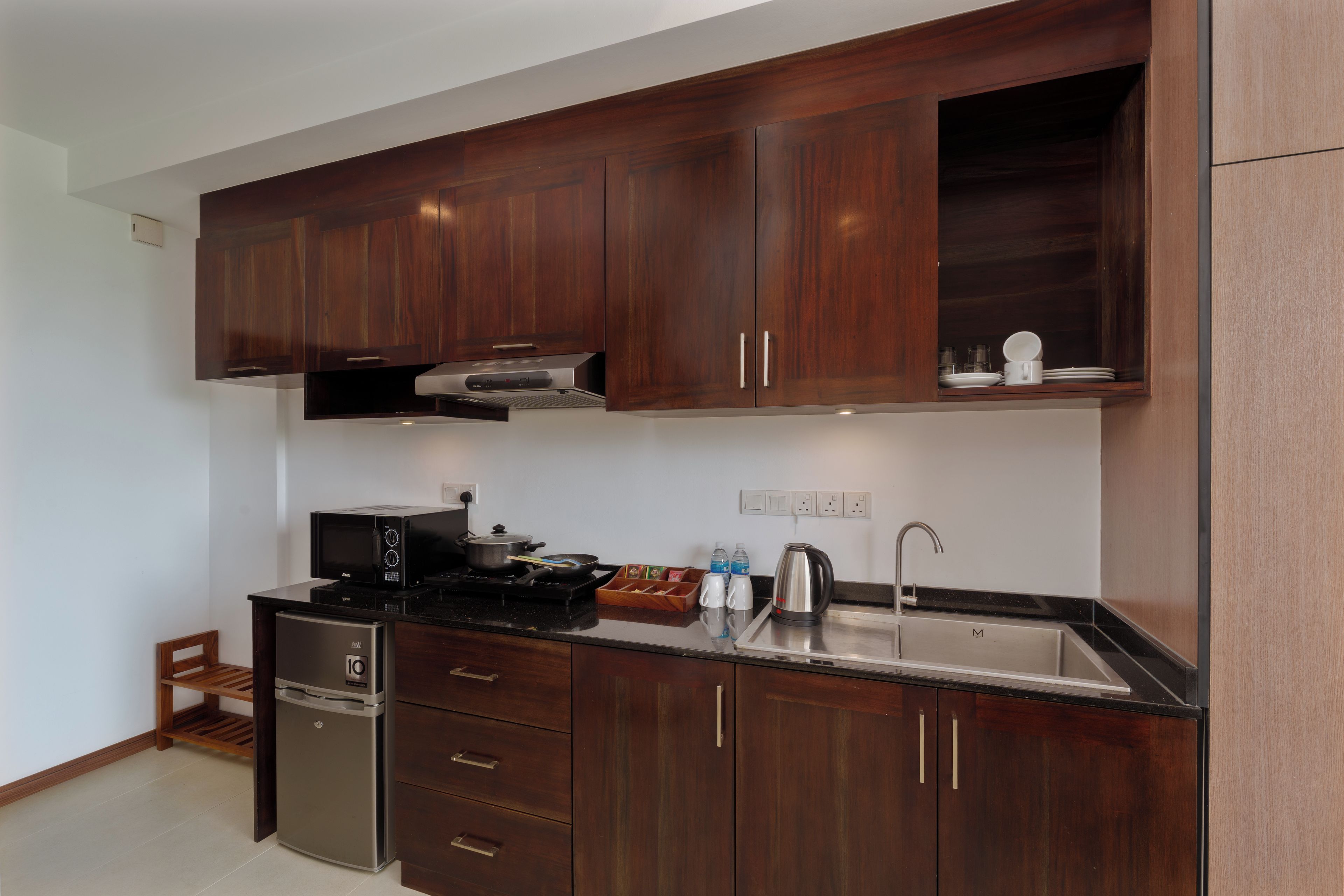 A modern kitchen with dark wood cabinets, stainless steel appliances, and a black countertop.