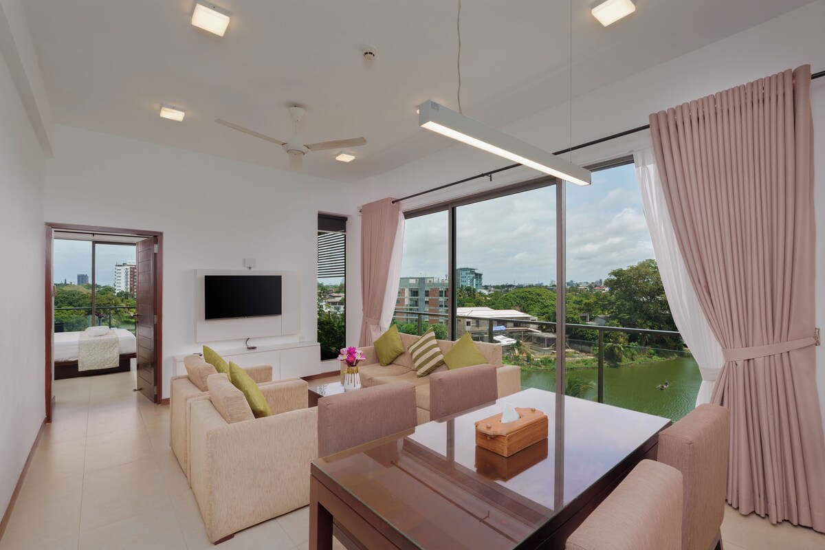 Una sala de estar moderna con un televisor de pantalla plana, sofás cómodos, una mesa de centro de vidrio y ventanas amplias con vista a la ciudad.