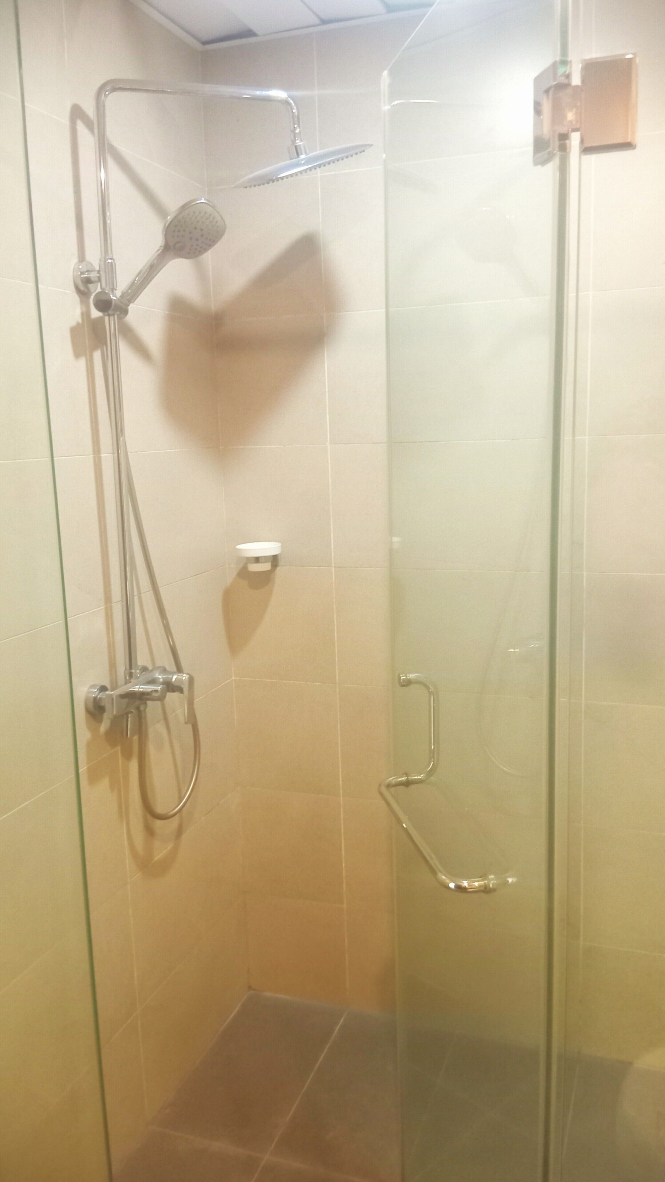 Eine Duschkabine mit Glaswänden, einer Handbrause, einer Wandarmatur und einer separaten Handdusche.