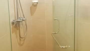 Eine Duschkabine mit Glaswänden, einer Handbrause, einer Wandarmatur und einer separaten Handdusche.