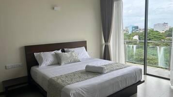 Una habitación de hotel moderna con una cama grande, vistas a una cascada y un balcón.
