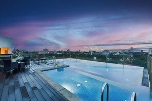 Una piscina infinita con vista a la ciudad al atardecer.