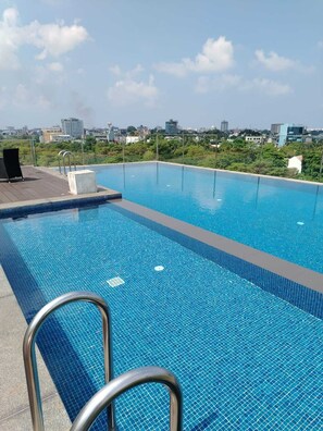 A rectangular swimming pool with clear blue water, surrounded by a tiled deck.