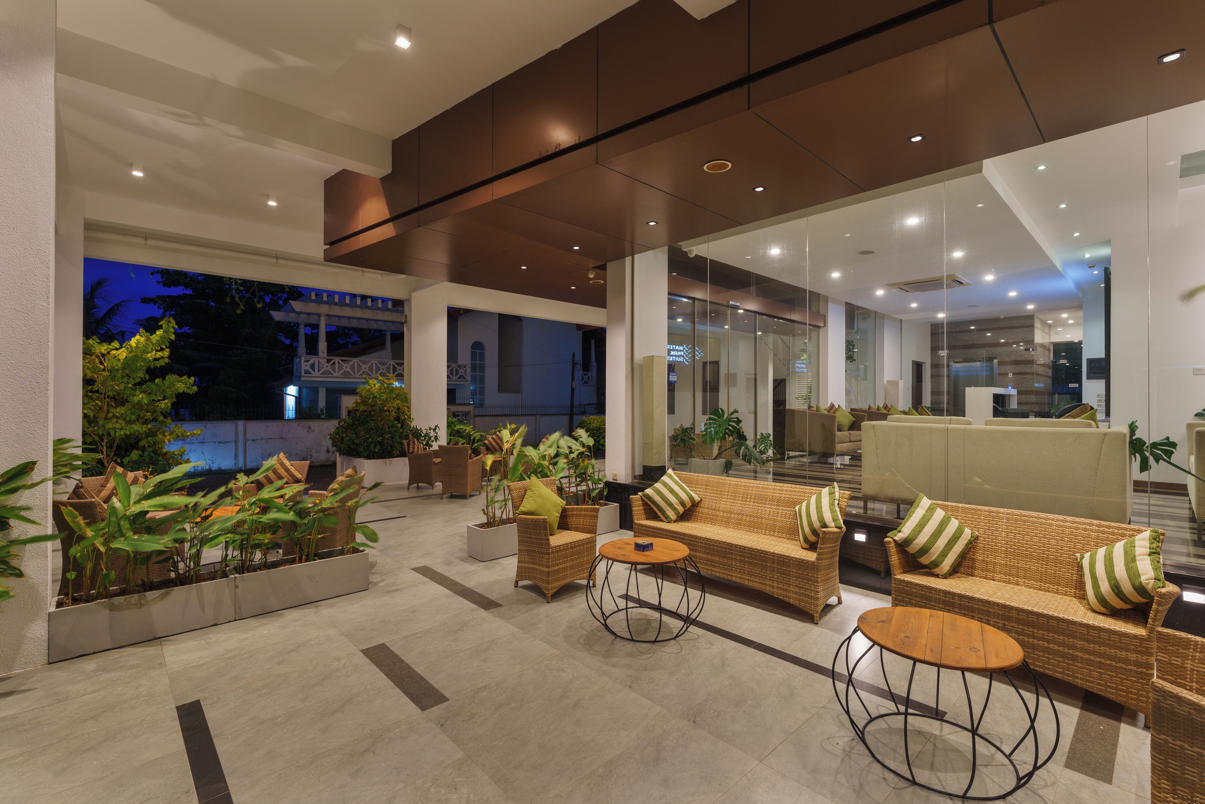 A modern lobby with wicker furniture, potted plants, and a view of the outside.