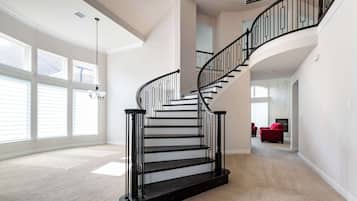 A spacious living area with a curved black staircase, large windows, and a red sofa.