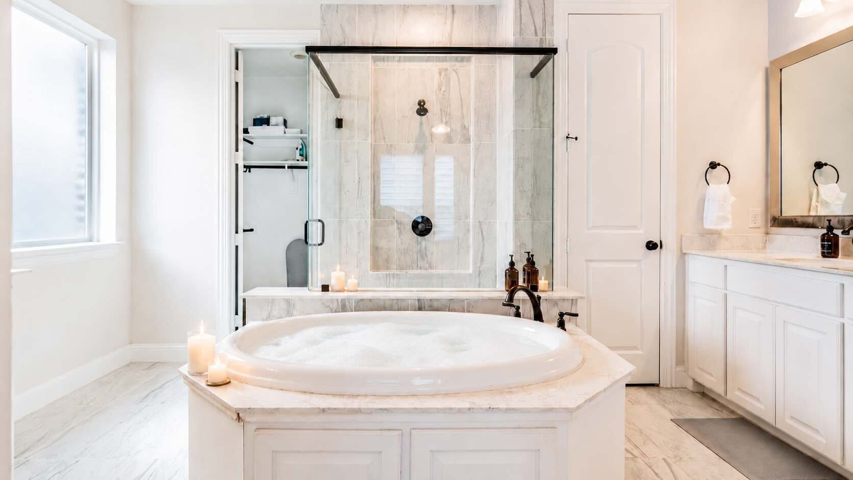 Une salle de bain moderne avec une baignoire sur pieds, une douche à parois de verre et un grand miroir.