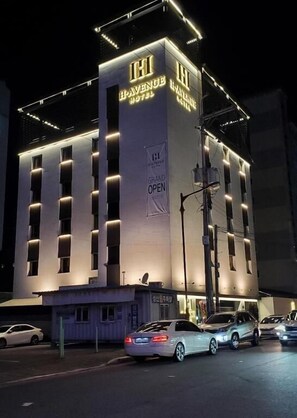 A hotel with a prominent 'HI' sign, multiple windows, and a 'GRAND OPEN' banner. - Gimhae H. Avenue (Gimhae)