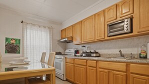 Une cuisine avec des meubles de rangement en bois, un four à micro-ondes, une cuisinière et une table à manger avec des chaises.