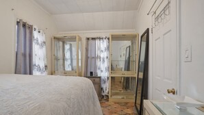 Une chambre à coucher comprenant un lit, une commode, un miroir et une salle de bain avec une baignoire.