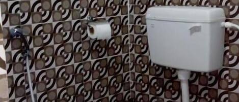 A bathroom with patterned walls, a toilet, and a blue floor.