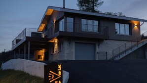Une maison moderne à deux étages, dotée d’un garage, d’un porche abrité et d’un escalier menant à l’étage supérieur.