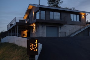 Ein modernes, zweistöckiges Haus mit Garage, überdachter Veranda und einer Treppe, die zum Obergeschoss führt.
