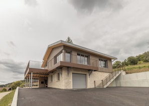 A modern two-story house with a flat roof, a balcony on the upper floor, and a garage. - Between the Lake and the Jura, Luxury Home—Sleeps 6—View of Lake St. Point: Luxury and Cozy Comfort (Les Grangettes)
