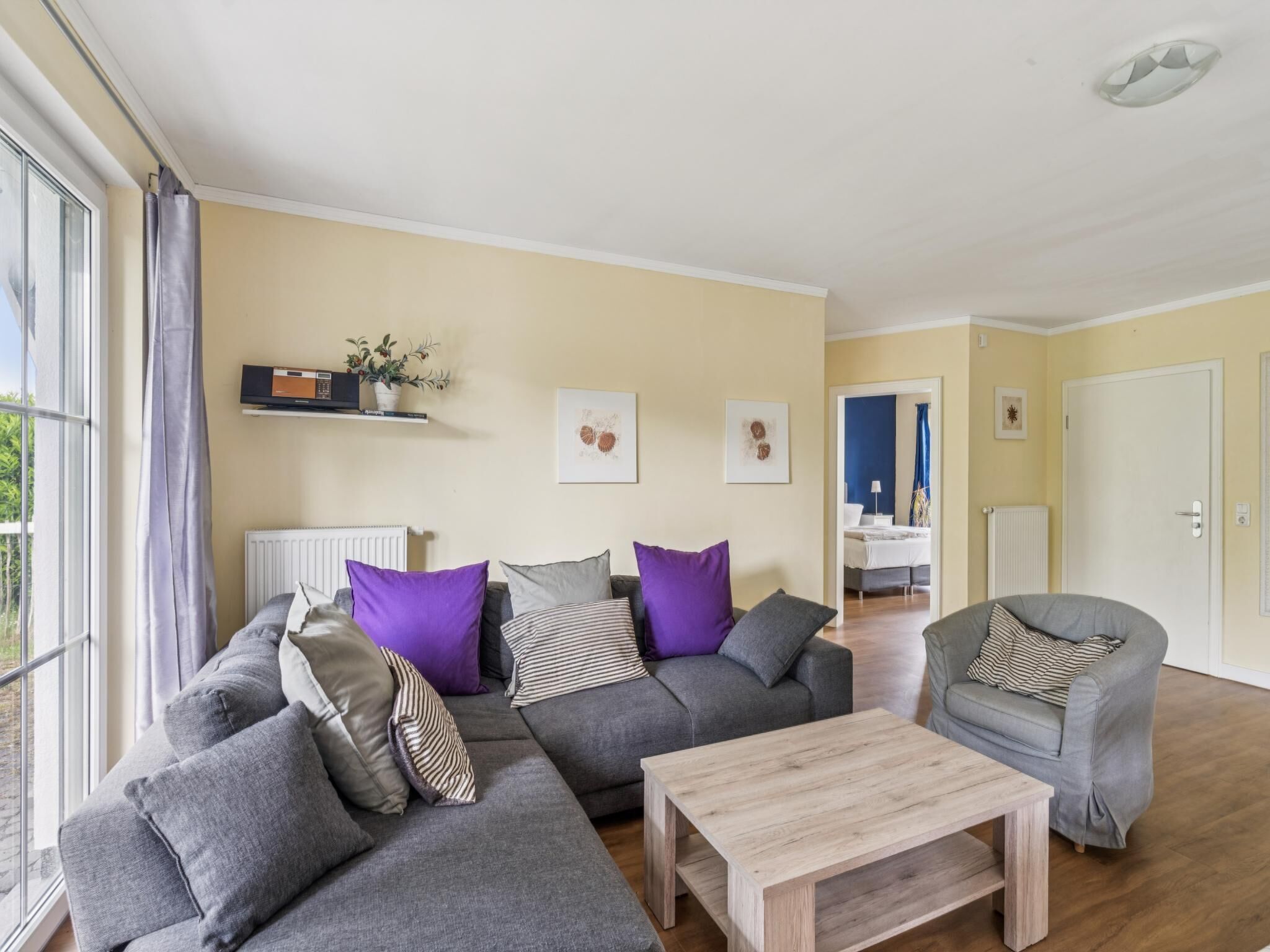 Ein Wohnzimmer mit einem grauen Sofa, einem Holztisch und einem grauen Sessel.