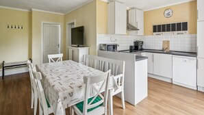 Pieni, käytännöllinen keittiö, jossa on valkoiset kaapit, mikroaaltouuni, kahvinkeitin ja seinäkello.