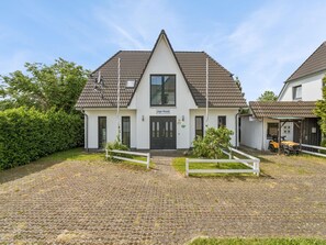 A two-story building with a tiled roof, a sign reading 'Jojo Huis,' and a paved driveway leading to the entrance. - Coastal Holiday Apartment near Kühlungsborn (Bastorf)