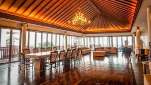 A spacious room with a large dining table, comfortable seating, and a chandelier.