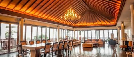A spacious room with a large dining table, comfortable seating, and a chandelier.