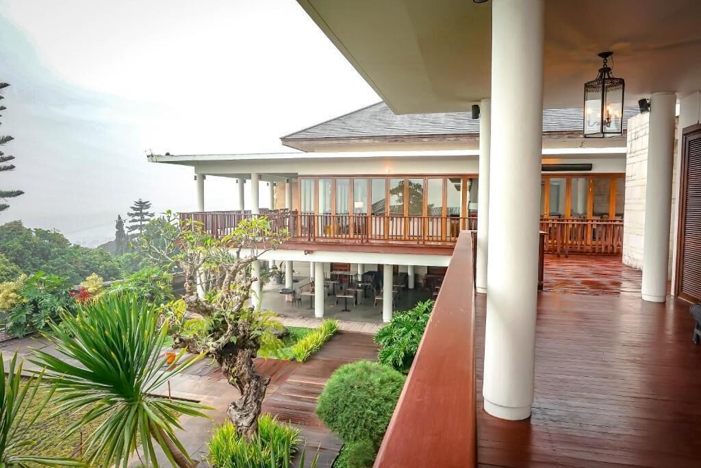 A hotel with a covered outdoor seating area, a wooden deck, and a view of the surrounding landscape.