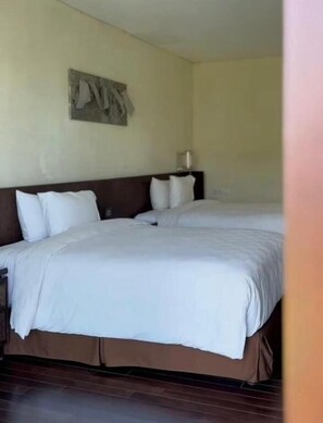 A hotel room with two beds, a headboard, a wall-mounted artwork, and a bedside table with a lamp. - Louis Kienne Bandungan (Bandungan)