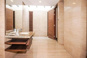 A modern bathroom with a marble floor, a built-in sink, and wooden doors.