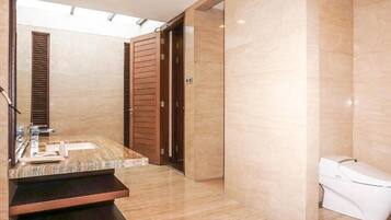 Uma casa de banho moderna com lavatório de mármore, portas de madeira e sanita.