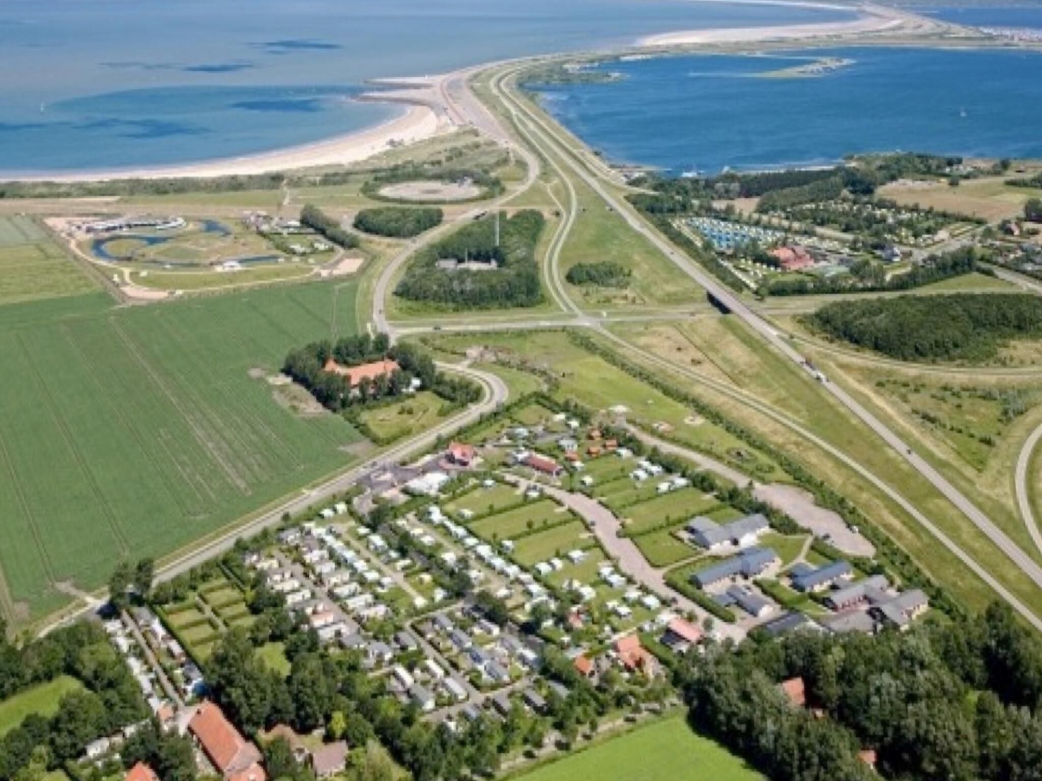 An aerial view of a coastal area with a marina, roads, and residential buildings.