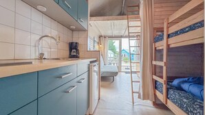 Cocina compacta con pileta, cafetera y alacenas. Una escalera lleva a una zona con literas y vistas al exterior.
