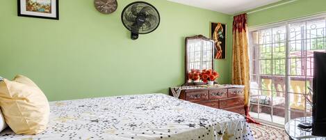 A bedroom with a bed, dresser, and a window with curtains.