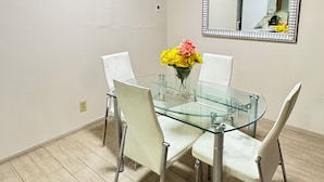 A dining area with a glass table, white chairs, a vase of flowers, an air conditioner, and a mirror on the wall. - Downtown Wonderful cozy’s 1-bedroom apartment with AC in charming San Antonio (San Antonio)