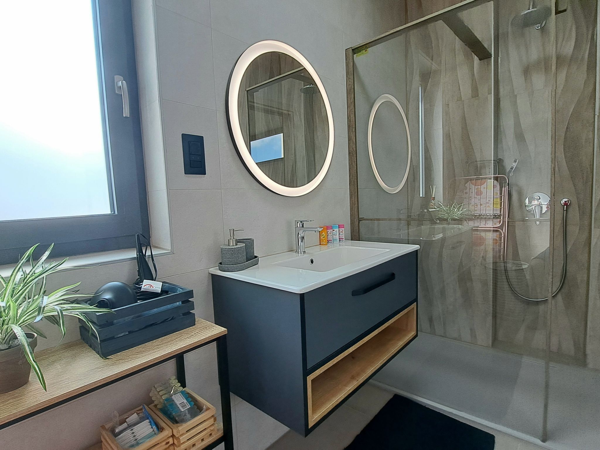 A modern bathroom with a large mirror, a sink, and a shower.