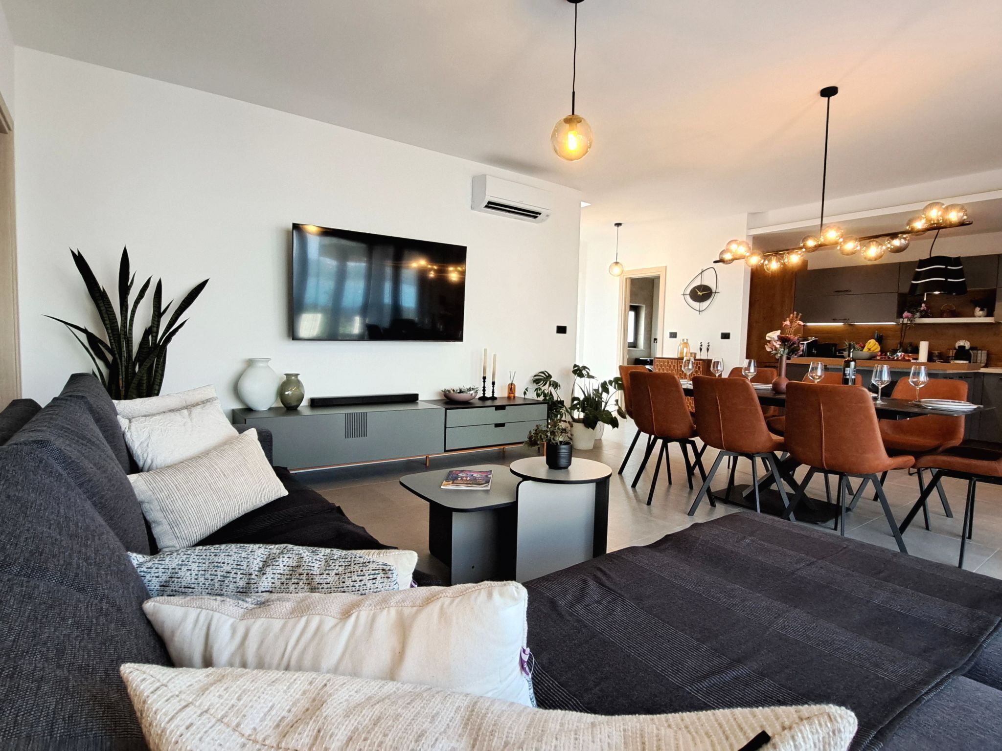 Una sala de estar moderna con un sofá, una mesa de centro y una zona de comedor con sillas.