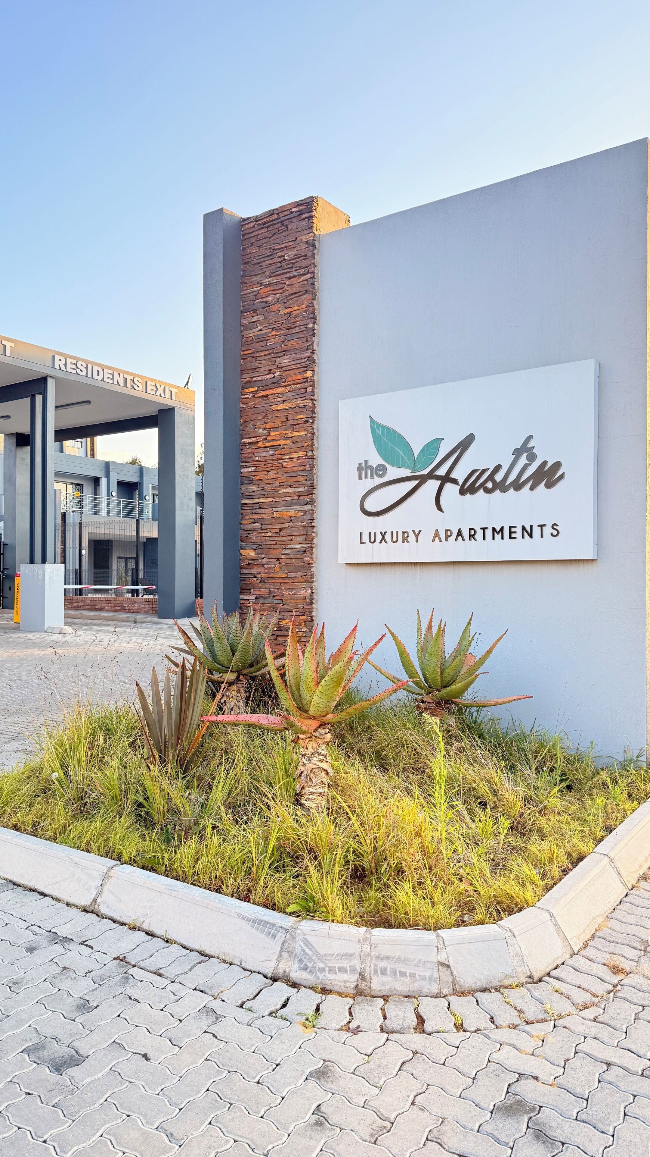 Letrero que dice 'Austin Luxury Apartments', con un edificio moderno al fondo.