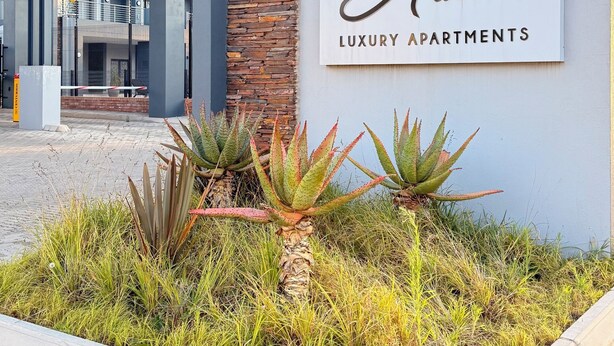 En skylt med texten ”Austin Luxury Apartments”, med en modern byggnad i bakgrunden.