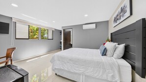 A modern bedroom with a large bed, a desk, and a chair. - Cozy Beach Escape - Steps from Manuel Antonio Beach - Economy Room (Manuel Antonio)
