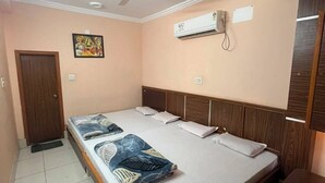Un dormitorio con cama, ventilador de techo, aire acondicionado, una puerta y un cuadro colgado en la pared.