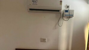 Una habitación de hotel con una cama, aire acondicionado de pared y un enchufe.