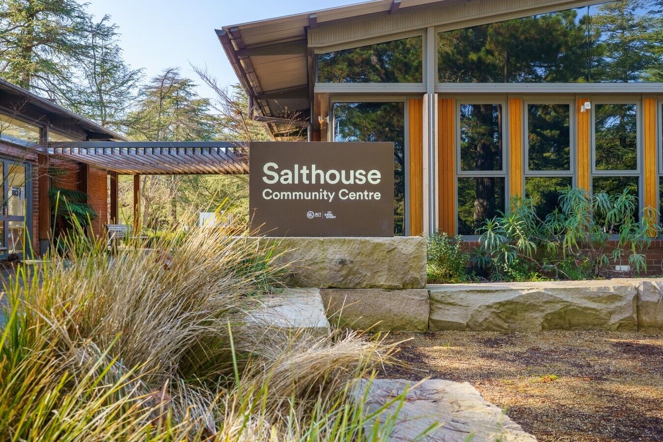 A building labeled 'Salthouse Community Centre' with a stone pathway, grassy area, and trees in the background.