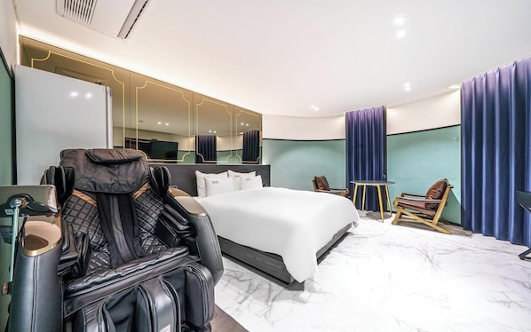 A hotel room with a bed, a massage chair, a desk with a chair, a mirror, and a television. - Hotel Again (Cheongju)